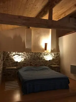 a bedroom with a bed in a stone wall at Gîte Le Ribet in Lempaut