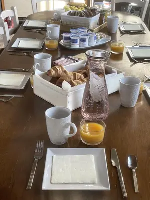 a wooden table with a plate of food and a vase at LAURAGUEL CHAMBRES D'HÔTES in Mourvilles-Hautes