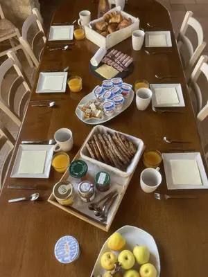 a wooden table with plates of food on it at LAURAGUEL CHAMBRES D'HÔTES in Mourvilles-Hautes