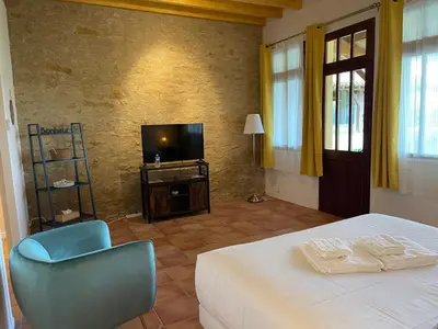 a bedroom with a bed and a chair and a television at LAURAGUEL CHAMBRES D'HÔTES in Mourvilles-Hautes