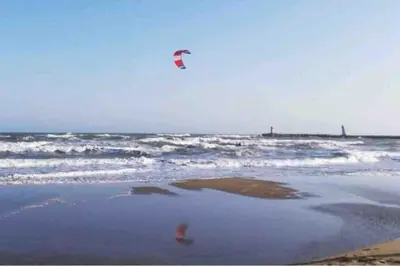 a person is flying a kite on the beach at Soleil Sucré T2 Centre historique de Narbonne in Narbonne