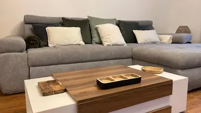 a living room with a gray couch with a table at L'Alcove in Carcassonne