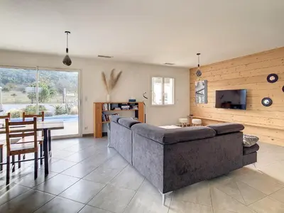 a living room with a large couch and a table at Le point BE - Magnifique villa avec piscine chauffée - de mai à septembre - pour 6 personnes in Ornaisons