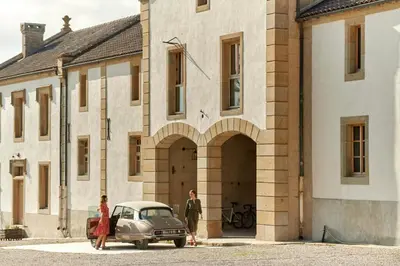 a man and a woman standing next to a car in front of a building at Dépendance de Sibra in Lagarde