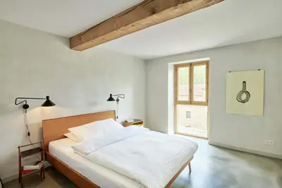 a white bedroom with a bed and a window at Dépendance de Sibra in Lagarde