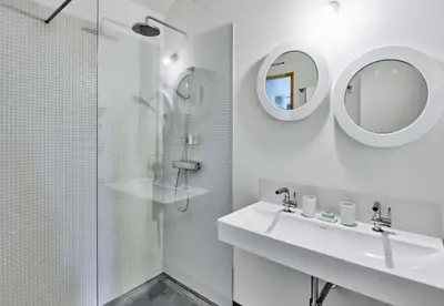 a white bathroom with a sink and a shower at Dépendance de Sibra in Lagarde