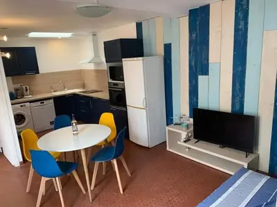 a kitchen with a table and chairs and a tv at Patio avec cour et place de parking en bord de mer in Port-la-Nouvelle