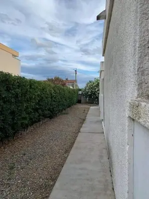 a sidewalk next to a wall next to a building at Patio avec cour et place de parking en bord de mer in Port-la-Nouvelle