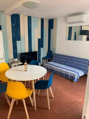 a room with a table and chairs and a bed at Patio avec cour et place de parking en bord de mer in Port-la-Nouvelle