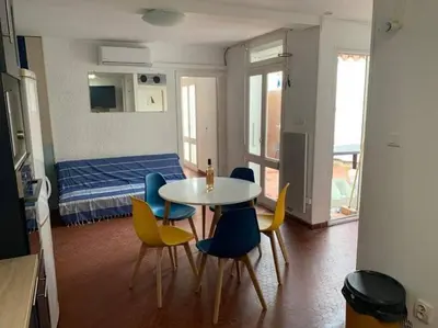 a room with a table and chairs and a bed at Patio avec cour et place de parking en bord de mer in Port-la-Nouvelle
