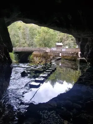 a bridge over a river with rocks in the water at Gîte l'Enclos Ô rendez-vous Roquefeuil-Pays de sault- avec jardin in Roquefeuil