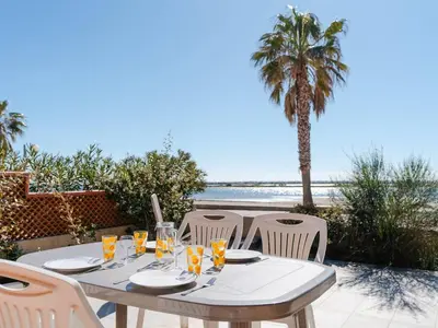 a table with chairs and a table with a view of the beach at Superbe Pavillon à Gruissan avec Terrasse sur Plage, 2 Chambres, Parking et Wifi - FR-1-409A-20 in Gruissan