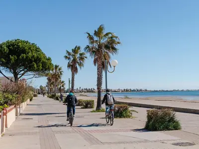 two people riding bikes down a sidewalk near the beach at Superbe Pavillon à Gruissan avec Terrasse sur Plage, 2 Chambres, Parking et Wifi - FR-1-409A-20 in Gruissan