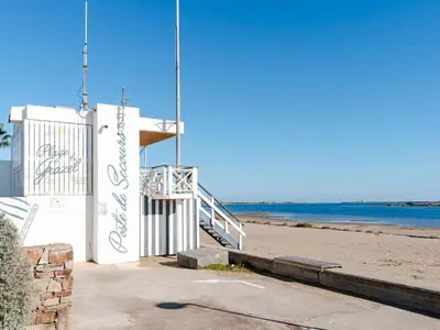 a building on a beach with the ocean in the background at Superbe Pavillon à Gruissan avec Terrasse sur Plage, 2 Chambres, Parking et Wifi - FR-1-409A-20 in Gruissan