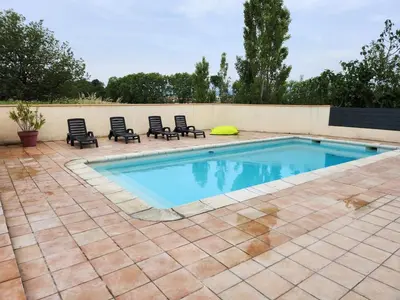 a swimming pool with four chairs and a wall at DOMAINE DE POULHARIES - Carignan in Carcassonne