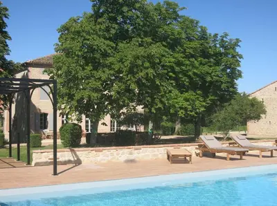 a swimming pool in front of a house with a tree at Bastide des Tourelles pour 20 pers. Piscine & Spa in Marzens