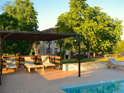a patio with chairs and a canopy next to a pool at Bastide des Tourelles pour 20 pers. Piscine & Spa in Marzens