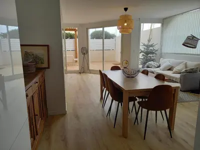 a kitchen and living room with a table and chairs at Appartement 100 m2 Terrasse Piscine in Gruissan
