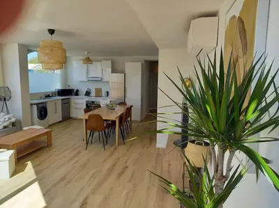 a kitchen and living room with a table and chairs at Appartement 100 m2 Terrasse Piscine in Gruissan