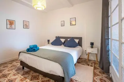 a bedroom with a large bed with blue pillows at Le Brodiaea Terrasse Wifi in Narbonne