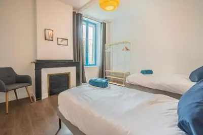 a room with two beds and a fireplace and a chair at Le Brodiaea Terrasse Wifi in Narbonne