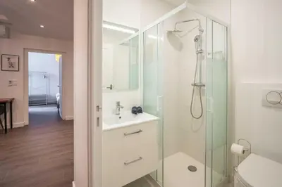 a white bathroom with a shower and a sink at Le Brodiaea Terrasse Wifi in Narbonne
