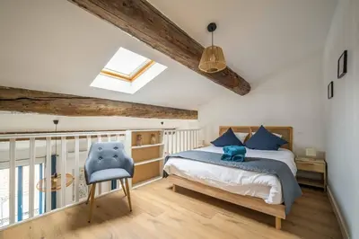 a bedroom with a bed and a blue chair at L'Apothicaire Proche des Halles in Narbonne