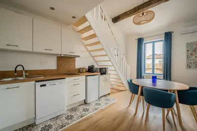 a kitchen with white cabinets and a table with chairs at L'Apothicaire Proche des Halles in Narbonne
