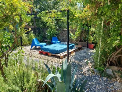 a patio with a bed and a bench in a garden at Chambres d'hôtes : Les maisons de Gaïa in Tuchan
