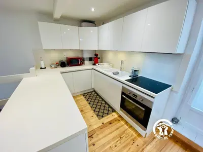 a kitchen with white cabinets and a wooden floor at Loft cocon climatisé - Imprenable vue sur le château Comtal in Carcassonne
