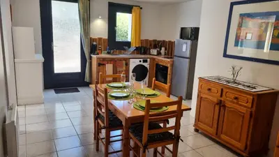 a kitchen with a table and chairs and a kitchen with a refrigerator at Appartement Signature - Design, Parking & Mer in Fitou