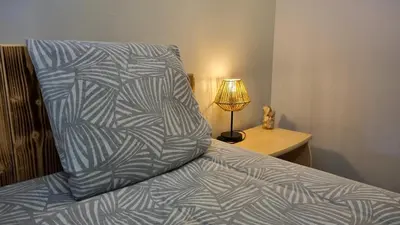 a bed with a blue and white blanket and a lamp at Appartement Signature - Design, Parking & Mer in Fitou