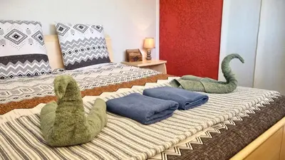 two stuffed dinosaurs are sitting on a bed at Appartement Signature - Design, Parking & Mer in Fitou