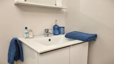 a bathroom with a sink and a blue towel at Appartement Signature - Design, Parking & Mer in Fitou