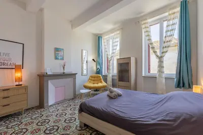 a bedroom with a bed and a fireplace and a chair at Maison de Vacances 8 à 15 pers à proximité du Canal du Midi in Sallèles-dʼAude