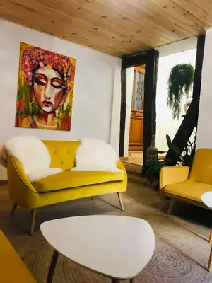a living room with a yellow couch and a painting at Hôte Labyrinthe sur la place chambres d, hôtes , calme ,Netflix in Mirepoix