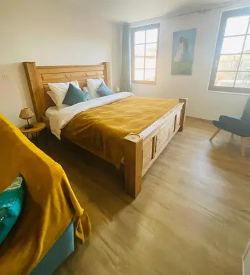 a bedroom with a large bed with a wooden headboard at Hôte Labyrinthe sur la place chambres d, hôtes , calme ,Netflix in Mirepoix
