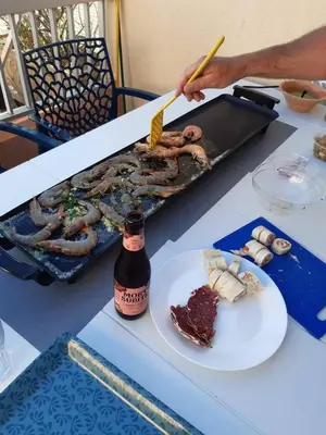 a table with a plate of meat and a bottle of beer at Appartement RDC vue mer - GRUISSAN in Gruissan