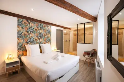 a bedroom with a large white bed and a bathroom at Le refuge de Saint-Gimer in Carcassonne