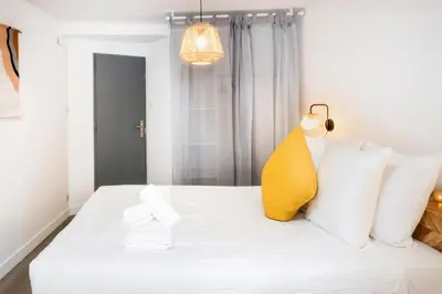 a bedroom with a white bed with a yellow pillow at Le refuge de Saint-Gimer in Carcassonne
