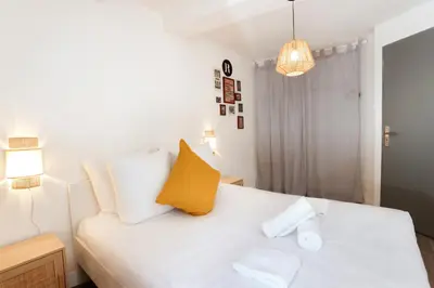a bedroom with a white bed with a yellow pillow at Le refuge de Saint-Gimer in Carcassonne