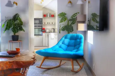 a blue chair in a living room with a table at Maison CABARET Luxury 4 Star Air Conditioned 100m to 4 Cathar Châteaux Lastours private Terrasse with views!! in Lastours