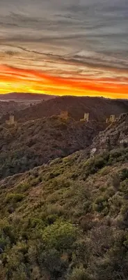 a sunset on top of a grassy hill at Maison CABARET Luxury 4 Star Air Conditioned 100m to 4 Cathar Châteaux Lastours private Terrasse with views!! in Lastours