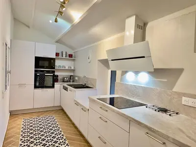 a white kitchen with white cabinets and appliances at Maison CABARET Luxury 4 Star Air Conditioned 100m to 4 Cathar Châteaux Lastours private Terrasse with views!! in Lastours