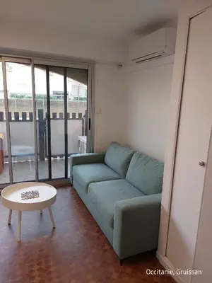 a living room with a blue couch and a table at Studio avec accès direct sur le port de Gruissan in Gruissan
