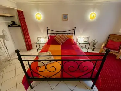 a bedroom with a bed with a red and orange blanket at Centre of Olonzac, 2 bedrooms & private sunny rooftop terrace in Olonzac
