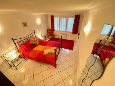 a view of a bedroom with a bed with red sheets at Centre of Olonzac, 2 bedrooms & private sunny rooftop terrace in Olonzac