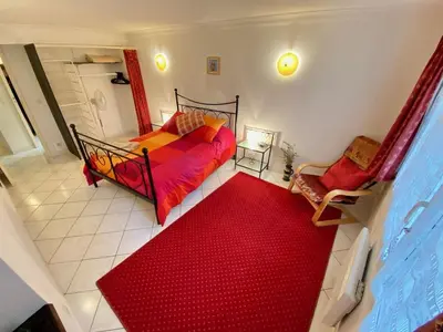 a bedroom with a red bed and a red carpet at Centre of Olonzac, 2 bedrooms & private sunny rooftop terrace in Olonzac