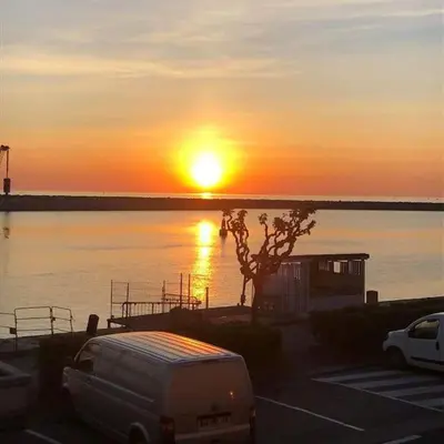 a sunset with a van parked in a parking lot at Appart T2 vue imprenable sur le canal et la mer in Port-la-Nouvelle