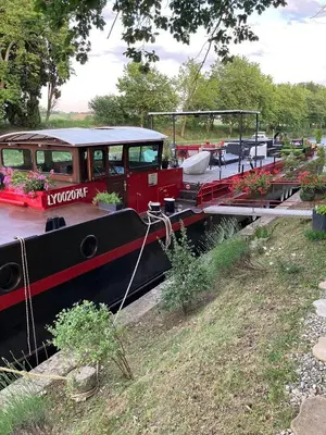 a small boat is parked next to a bridge at Péniche Mirage-chambre d'hôtes in Carcassonne